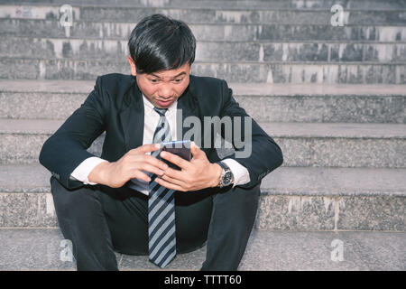 Gli imprenditori asiatici con mal di testa o emicrania presso il municipio dopo le immagini di lavoro di giovani imprenditori che sono stanchi, stress, crisi, depressione, failu Foto Stock