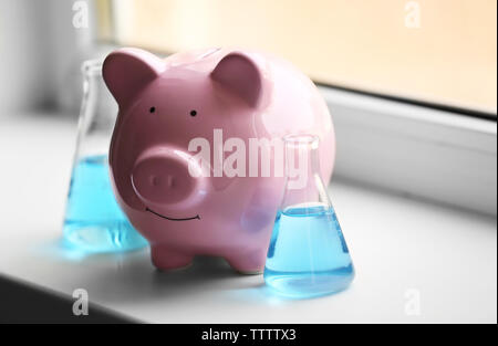 Maiale casella di denaro e i tubi con acqua sul davanzale Foto Stock