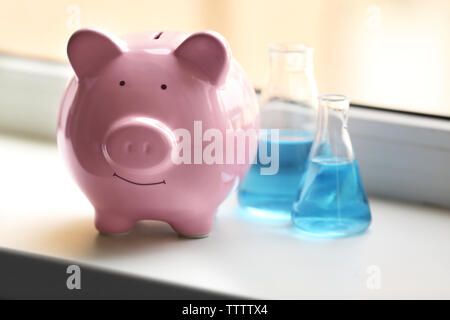 Maiale casella di denaro e i tubi con acqua sul davanzale Foto Stock