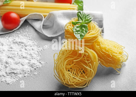 Pasta secca nidi con basilico sul tavolo Foto Stock