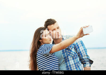 Bella coppia Giovane tenendo selfie sulla riva del fiume Foto Stock