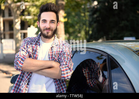 Successo giovane uomo in piedi accanto a AUTO Foto Stock