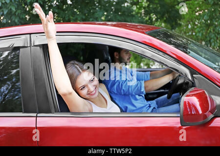 Piuttosto giovane donna sventolare attraverso aprire la finestra auto Foto Stock