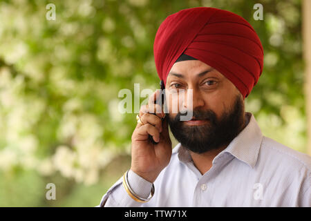 Indiano uomo sikh a parlare su un telefono mobile Foto Stock