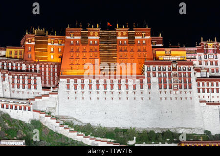 In prossimità della parte principale del palazzo del Potala di notte (Lhasa, in Tibet). Cielo nero, la bandiera cinese sventola sulla sommità del palazzo, rossa e bianca facciata illuminata. Foto Stock