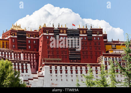In prossimità della parte principale del palazzo del Potala con possenti nuvola bianca in background. La bandiera nazionale della Cina onde sulla sommità del palazzo (Lhasa, in Tibet) Foto Stock