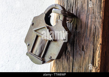 Interessante il vecchio lucchetto su una tavola di legno porta medioevale. Lucchetto vintage. Foto Stock