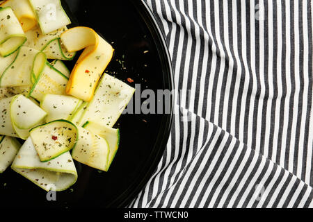 Fette di zucchine con condimento su piastra nera Foto Stock