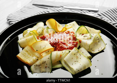 Fette di zucchine con condimento su piastra nera Foto Stock