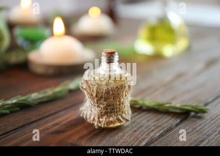 Bottiglia di olio essenziale di rosmarino sul tavolo di legno Foto Stock