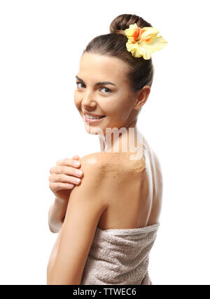 Bella giovane donna in asciugamano scrub applicando sul suo corpo, isolato su bianco Foto Stock