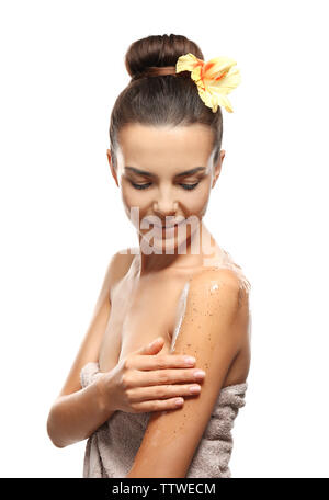 Bella giovane donna in asciugamano scrub applicando sul suo corpo, isolato su bianco Foto Stock
