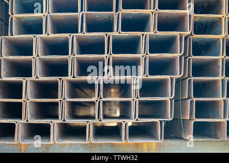 Rusty rettangolare tubo metallico in pacchi vengono memorizzati in metallo prodotti in magazzino vicino. Materiali a base di acciaio, costruzione materiali di consumo. Foto Stock