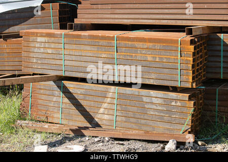 Rusty rettangolare tubo metallico in pacchi vengono memorizzati in metallo prodotti in magazzino vicino. Materiali a base di acciaio, costruzione materiali di consumo. Foto Stock