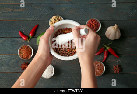 Mani femminili macinazione di spezie nel mortaio Foto Stock