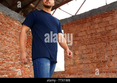 Giovane uomo nel fustellato t-shirt contro un muro di mattoni, primo piano Foto Stock