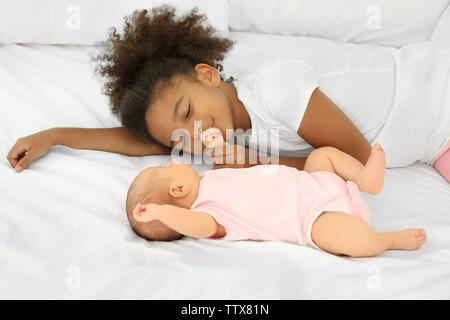 Carino il bambino e la sorella maggiore sul letto Foto Stock