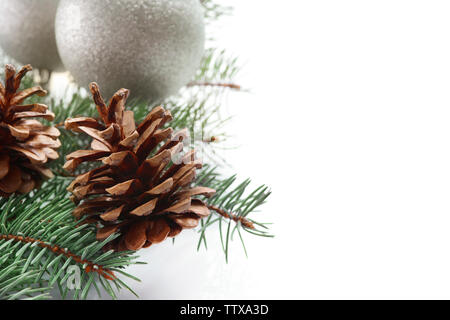 Composizione della bella baubles, coni e ramo di conifere su sfondo bianco, vista ravvicinata Foto Stock