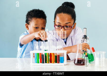 Due curiose americano africano bambini condurre interessanti esperimenti di chimica con liquidi colorati mentre l apprendimento delle scienze in laboratorio Foto Stock