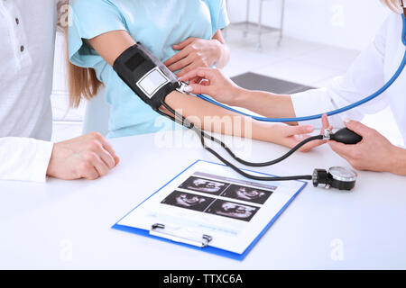 Medico la misura della pressione del sangue di donna in stato di gravidanza Foto Stock
