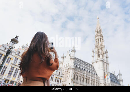 Viaggiare in Europa, giovane donna prendendo foto di mobile smart phone al grand-Palace di Bruxelles in Belgio in estate Foto Stock