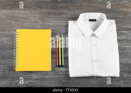 Uniformi scolastiche e accessori su sfondo di legno Foto Stock