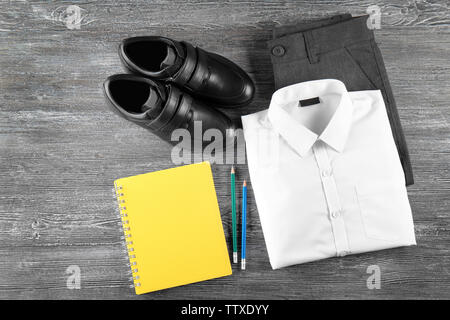 Uniformi scolastiche e accessori su sfondo di legno Foto Stock