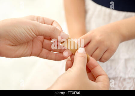 Incarto donna cerotto intorno bambina del dito, vista ravvicinata Foto Stock