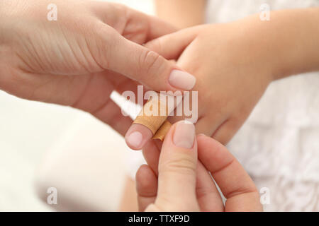 Incarto donna cerotto intorno bambina del dito, vista ravvicinata Foto Stock