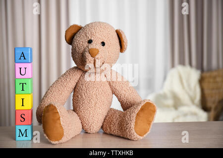 In legno colorato a cubetti con Teddy bear sul tendine dello sfondo. Concetto di autismo Foto Stock