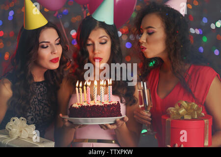 Bella giovani donne soffiando le candeline sulla torta di compleanno a parte Foto Stock