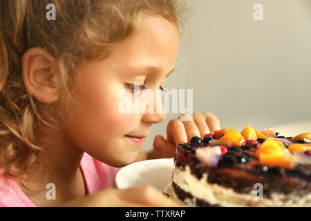 Carino bambina andando a gusto dolce torta, vista ravvicinata Foto Stock