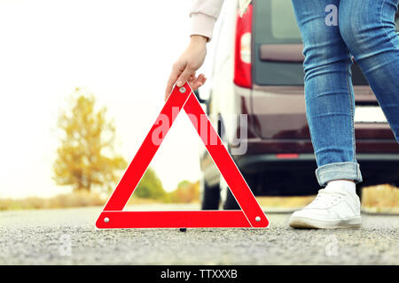 Driver femminile mettendo fuori del traffico segno di avvertimento sulla strada Foto Stock