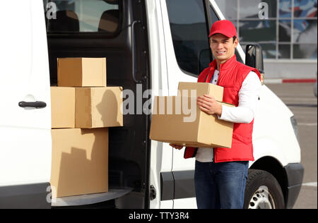 Giovane maschio con corriere pacchi vicino al servizio di consegna van Foto Stock
