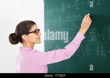 Giovane insegnante femminile accanto a lavagna Foto Stock