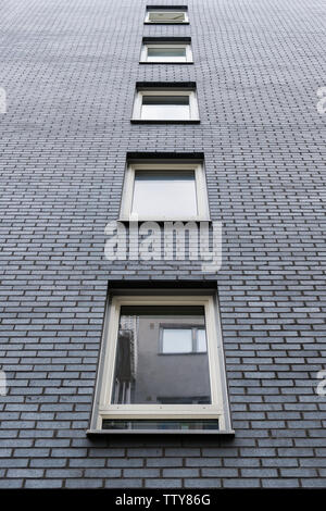 Windows su grigio scuro mattone sulla facciata appartamento Foto Stock