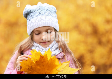 Ragazza carina con bouquet di foglie di acero su sfondo sfocato Foto Stock