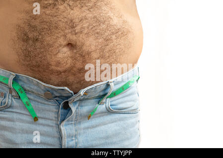 Un uomo misure il suo grasso ventre con un nastro di misurazione. su uno sfondo bianco. Foto Stock