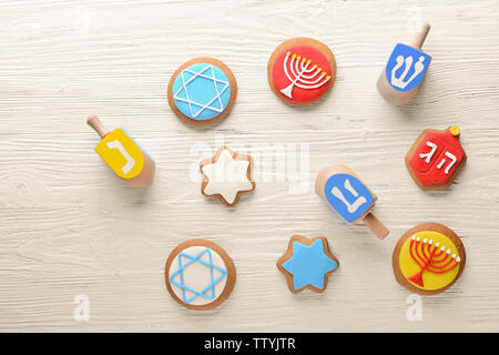 Gustosi biscotti vetrata e dreidels per Hanukkah luce sul tavolo di legno Foto Stock