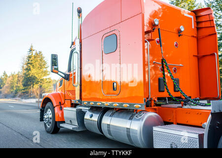 Arancio brillante classico americano iconico big rig long haul professionale potente confortevole semi carrello il trasporto commerciale cargo in semi rimorchio dri Foto Stock