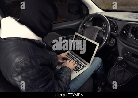 Ladro di auto di hacking di sistemi di sicurezza con computer portatile Foto Stock