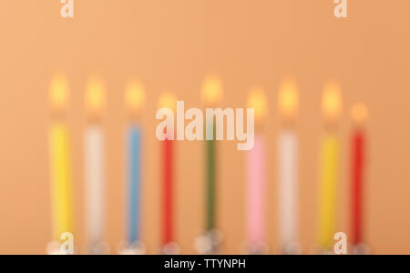 Vista offuscata di nove candele accese sul colore di sfondo. Hanukkah concept Foto Stock