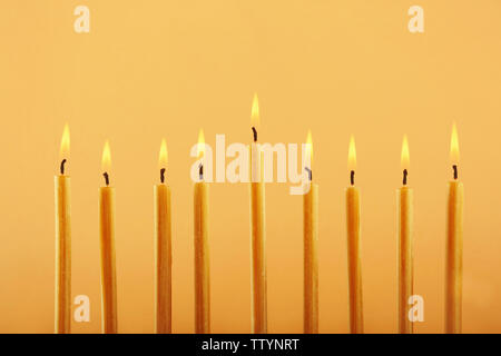 Nove candele accese sul colore di sfondo. Hanukkah concept Foto Stock