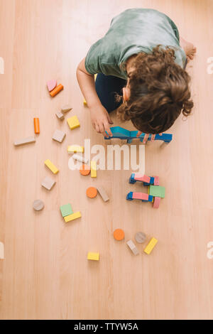 Vista dall'alto di una bambina gioca nel pavimento di legno colorati blocchi di costruzione giocattoli a casa o asilo nido, giocattoli educativi per bambini creativi Foto Stock