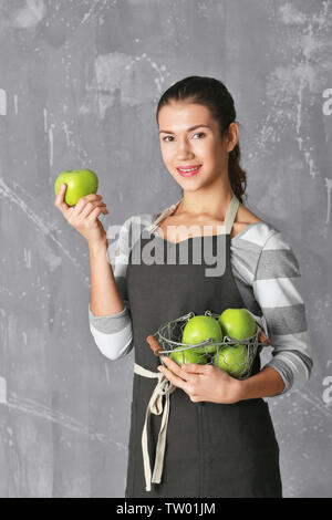 Donna che mantiene le mele nel cestello sul colore di sfondo Foto Stock