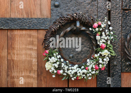 Bella corona di fiori appesi sulla vecchia maniglia della porta Foto Stock