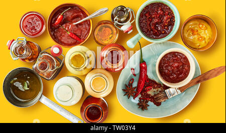 Giallo variopinto panorama di salse e marinate in bottiglia, vasi e ciotole con peperoncino e spezie pronto per un barbecue estivo visto dall'alto verso il basso Foto Stock