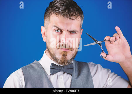 Imprenditore faccia rigorosa tenere forbici. Barbiere con la barba e baffi tenere Forbici in acciaio. Toelettatura barba. Crea il tuo stile. Macho barbuto barbiere forbici per tenere i capelli tagliati. Barbiere il concetto di servizio. Foto Stock