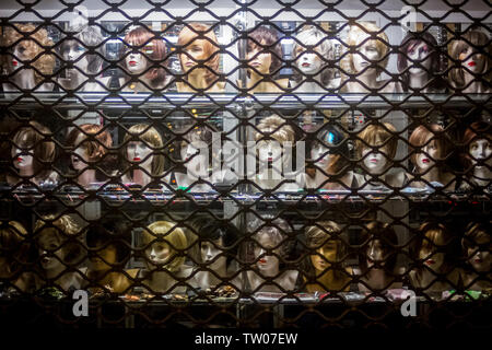 Parrucche visualizzato sul manichino teste in una vetrina di notte a Poznan, Polonia Foto Stock