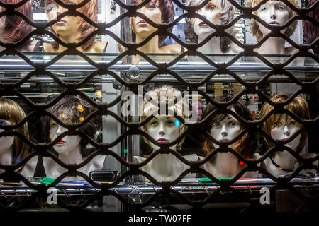 Parrucche visualizzato sul manichino teste in una vetrina di notte a Poznan, Polonia Foto Stock